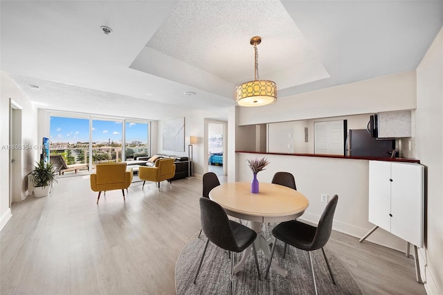 dining space featuring a raised ceiling, hardwood / wood-style floors, and a textured ceiling