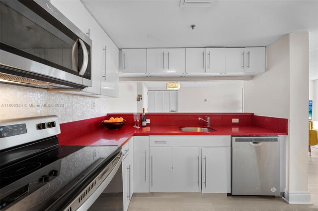 kitchen with appliances with stainless steel finishes, tasteful backsplash, white cabinetry, and sink