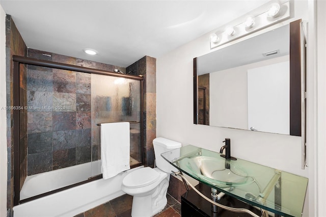 full bathroom with combined bath / shower with glass door, vanity, tile patterned flooring, and toilet