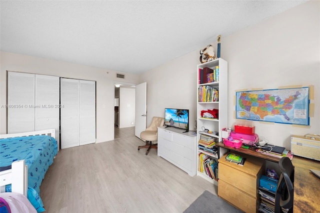 bedroom featuring a textured ceiling, light hardwood / wood-style flooring, and a closet