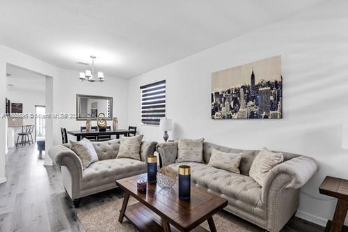 living room featuring wood-type flooring and an inviting chandelier