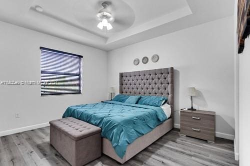 bedroom featuring wood-type flooring, ceiling fan, and a tray ceiling