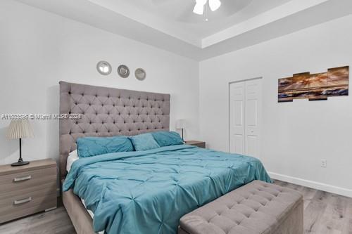 bedroom with a tray ceiling, a closet, ceiling fan, and hardwood / wood-style floors