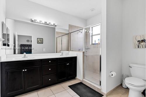 bathroom with dual vanity, walk in shower, toilet, and tile floors