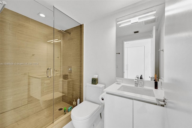 bathroom featuring a shower with door, vanity, and toilet