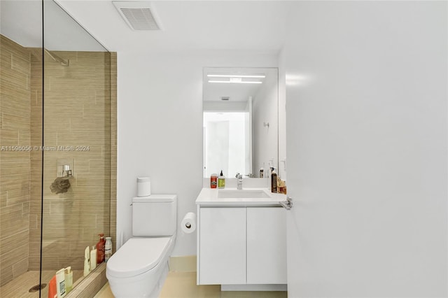 bathroom with vanity, a tile shower, and toilet