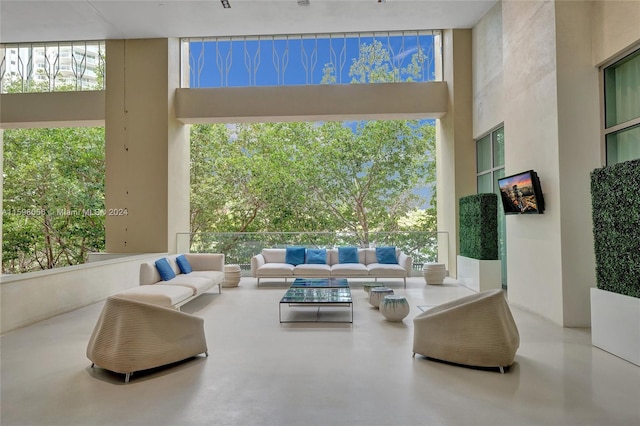 living room with expansive windows, a towering ceiling, and concrete floors