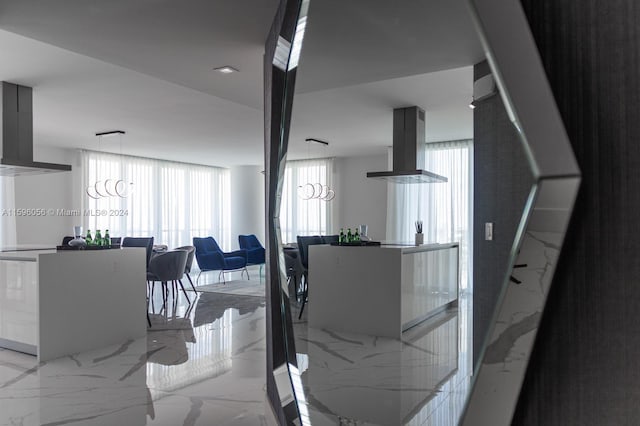 interior space with wall chimney range hood, island range hood, and a notable chandelier