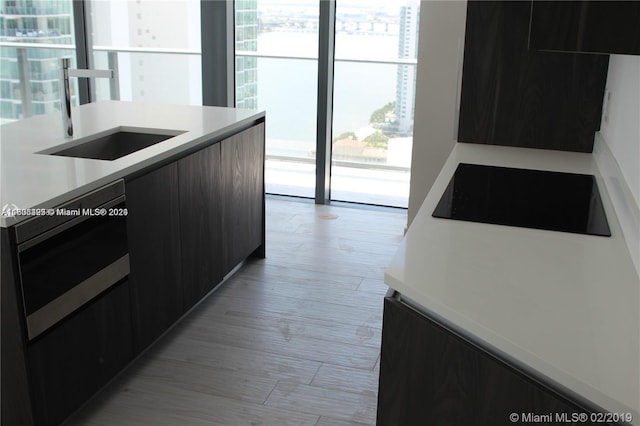 kitchen featuring sink, cooktop, and light wood-type flooring