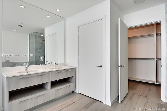 bathroom with oversized vanity, dual sinks, and hardwood / wood-style flooring