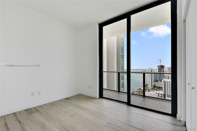 unfurnished room featuring light hardwood / wood-style flooring and floor to ceiling windows