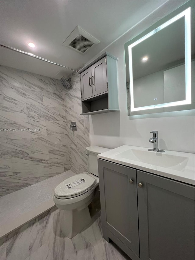 bathroom with vanity, toilet, and tiled shower