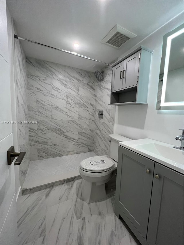 bathroom with vanity, tiled shower, and toilet