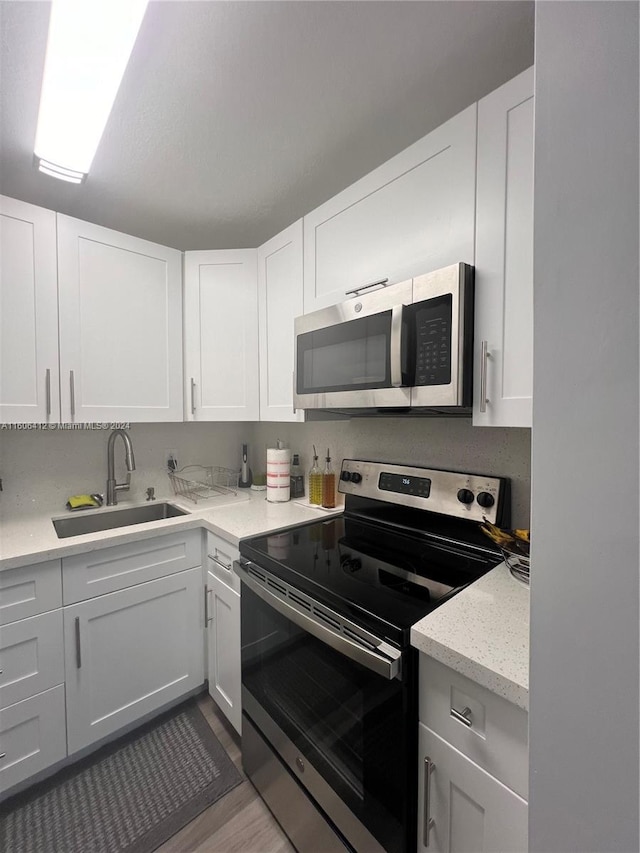 kitchen featuring light stone counters, appliances with stainless steel finishes, sink, and white cabinets