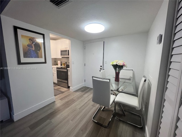 dining space with light hardwood / wood-style flooring and a textured ceiling