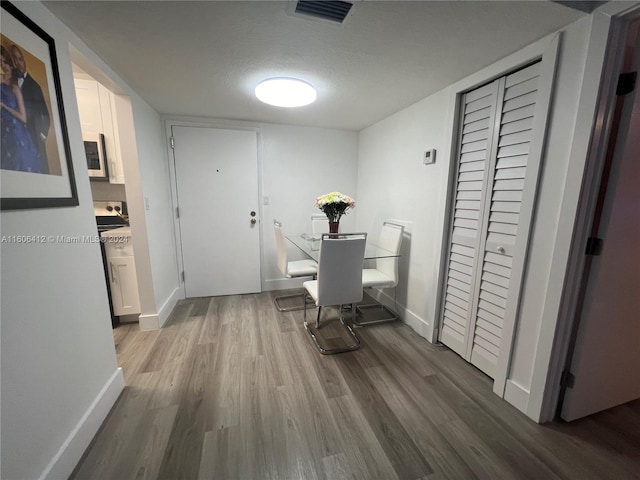 dining room with wood-type flooring and a textured ceiling