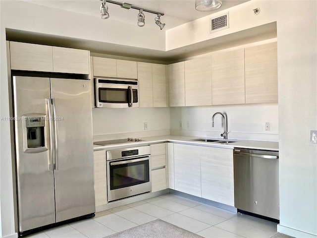 kitchen with appliances with stainless steel finishes, sink, track lighting, and light tile patterned floors