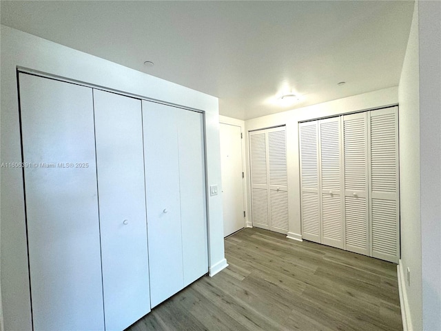 4250 Biscayne Blvd Unit 806, Miami, FL 33137 - unfurnished bedroom featuring baseboards, multiple closets, and wood finished floors