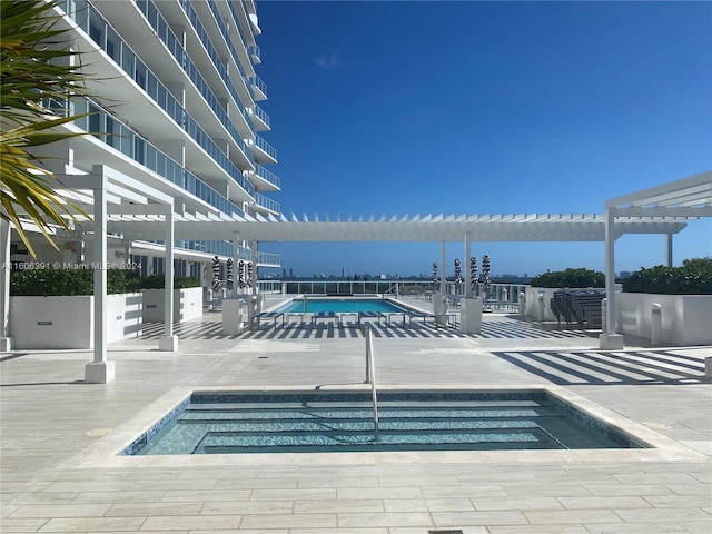 view of swimming pool featuring a community hot tub, a patio area, and a pergola