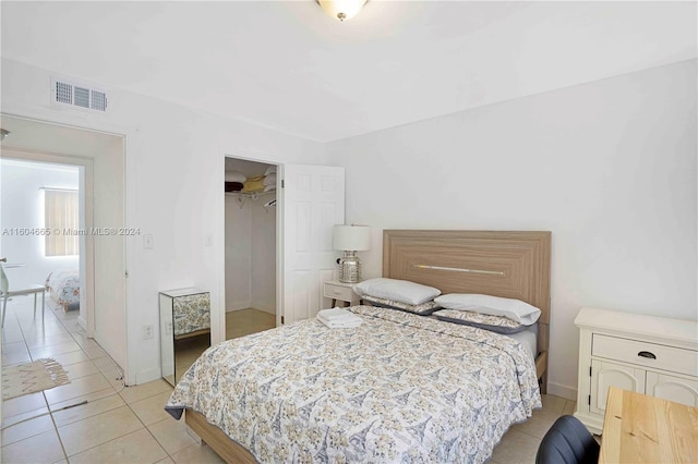 tiled bedroom with a walk in closet and a closet