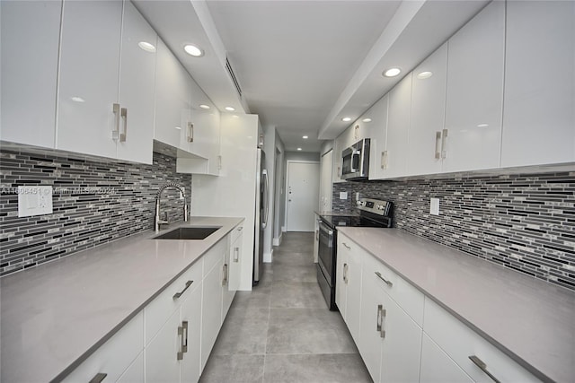 kitchen featuring backsplash, white cabinets, sink, light tile floors, and appliances with stainless steel finishes