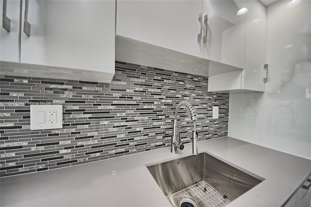 kitchen featuring backsplash, white cabinets, and sink