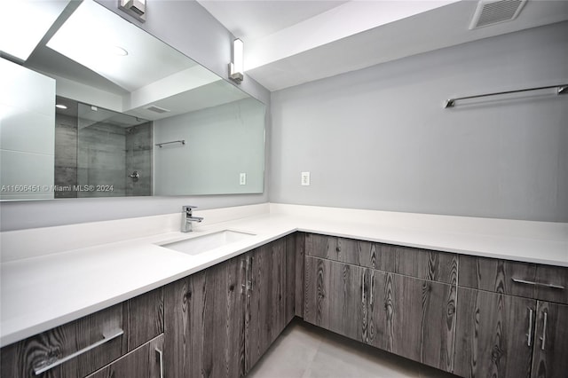 bathroom featuring a tile shower, tile flooring, and oversized vanity