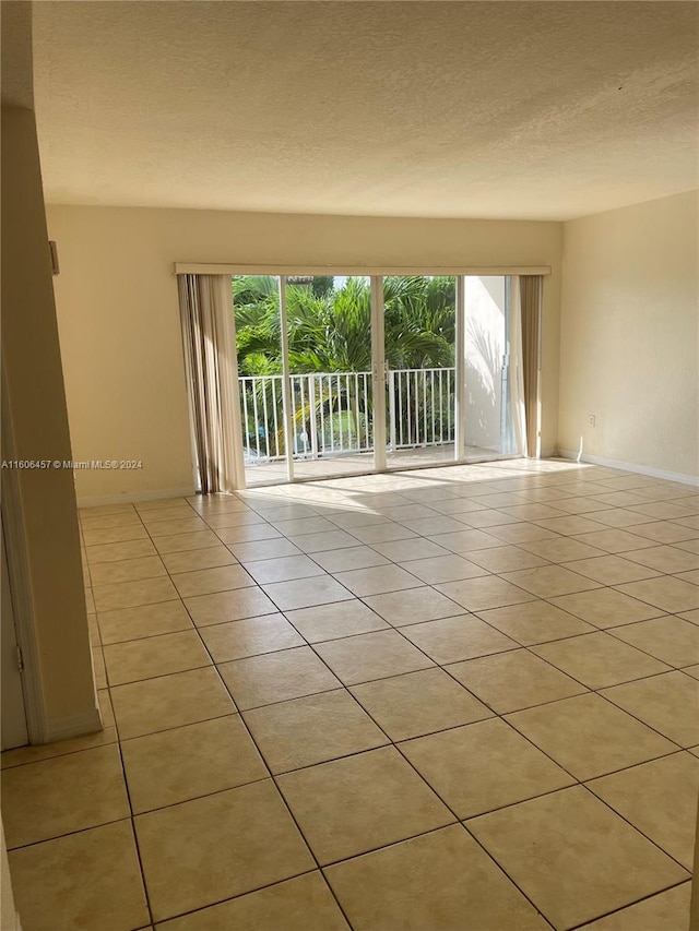 tiled empty room featuring a textured ceiling