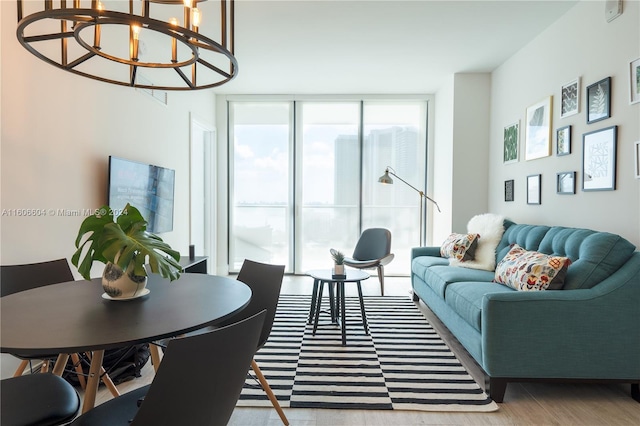 living room with light hardwood / wood-style floors, an inviting chandelier, and a wall of windows