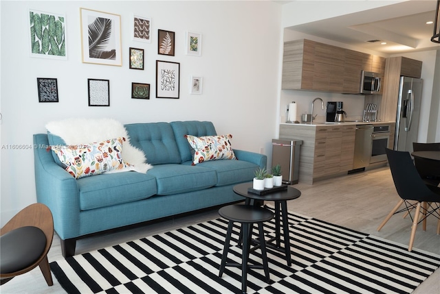 living room featuring sink and light hardwood / wood-style floors