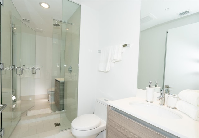 bathroom featuring tile patterned flooring, vanity, a shower with shower door, and toilet