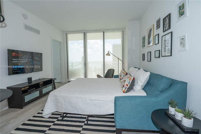 bedroom with hardwood / wood-style flooring and expansive windows