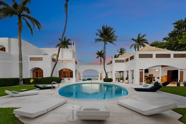 pool at dusk with a patio area