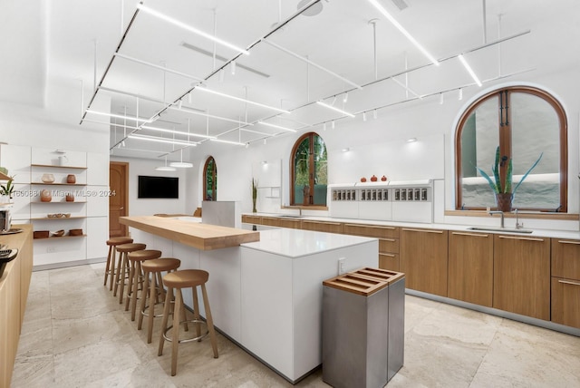 kitchen featuring sink, a kitchen island, light tile floors, and a kitchen bar