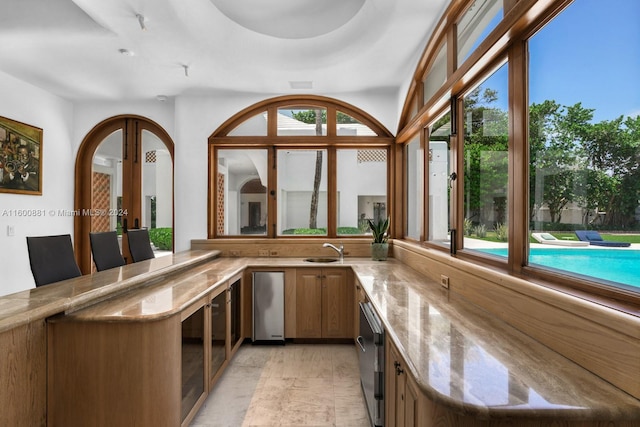 bar with light stone countertops, sink, and light tile flooring