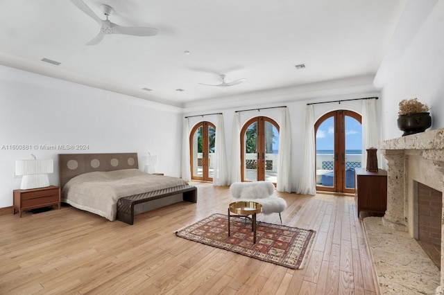 bedroom with a high end fireplace, ceiling fan, french doors, light hardwood / wood-style floors, and access to exterior