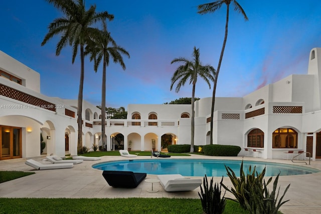 pool at dusk featuring a patio area