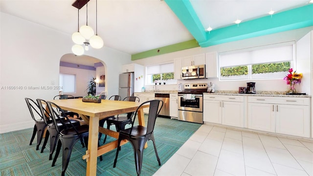 kitchen featuring white cabinets, light tile patterned floors, appliances with stainless steel finishes, light stone counters, and pendant lighting