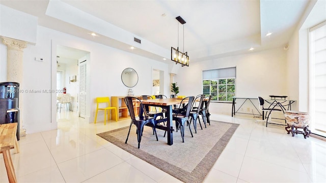 tiled dining space featuring an inviting chandelier and a tray ceiling