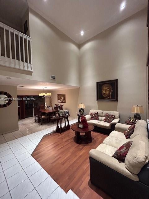 living room featuring a towering ceiling, light tile patterned floors, and a notable chandelier