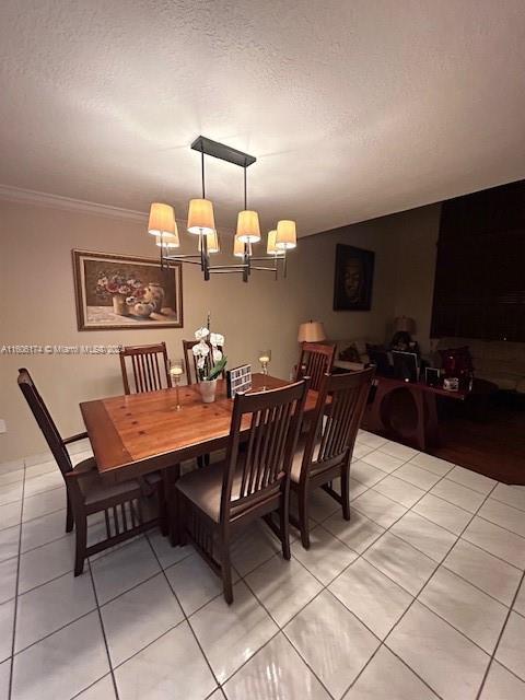 tiled dining area featuring crown molding, a textured ceiling, and a notable chandelier