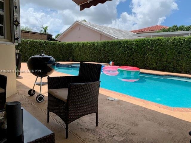 view of pool featuring an in ground hot tub, a patio area, and a grill