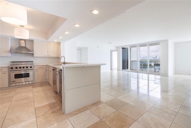 kitchen with backsplash, kitchen peninsula, wall chimney exhaust hood, appliances with stainless steel finishes, and a wall of windows