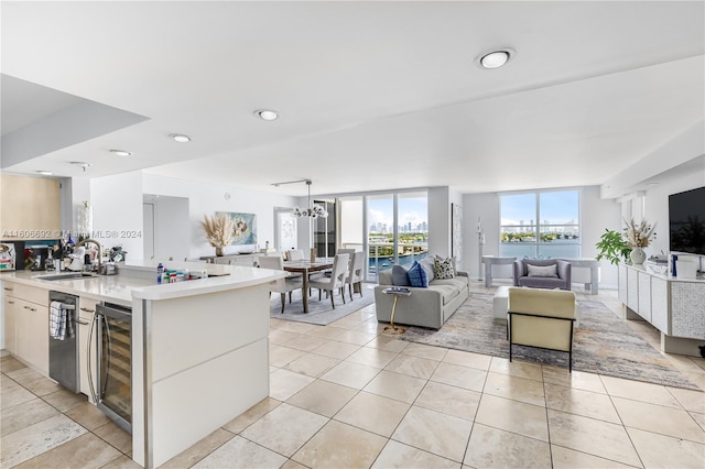 kitchen with expansive windows, sink, stainless steel dishwasher, light tile patterned flooring, and beverage cooler