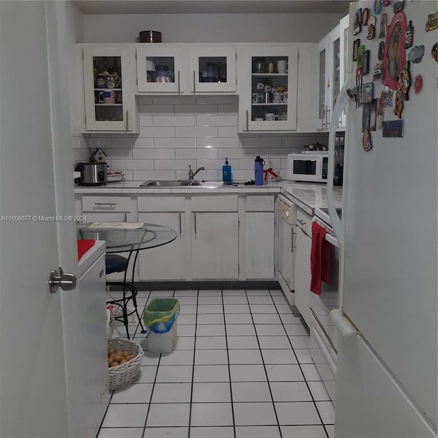 kitchen with backsplash, white appliances, light tile patterned floors, and white cabinets