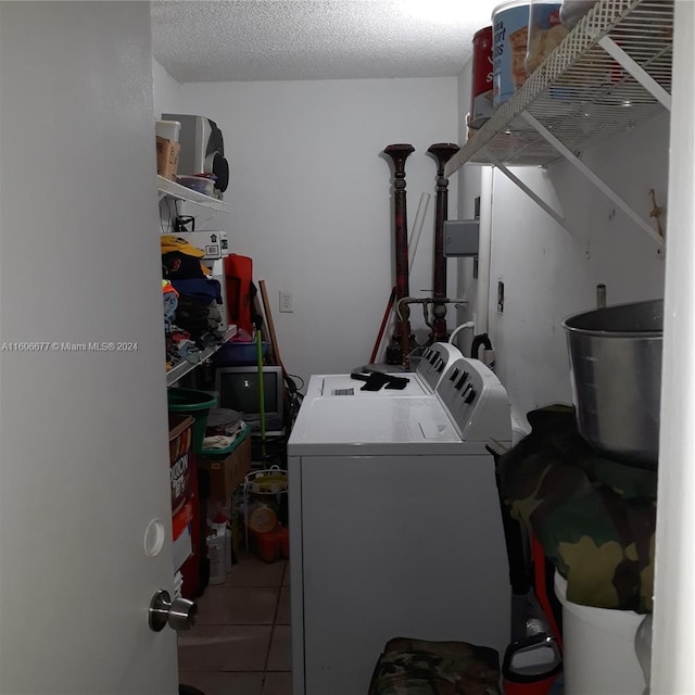 washroom featuring separate washer and dryer, light tile patterned floors, and a textured ceiling