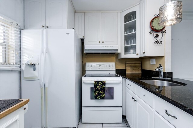 kitchen with tile flooring, white appliances, dark stone countertops, sink, and white cabinets