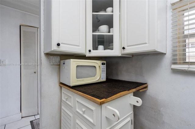 kitchen with crown molding, white cabinets, and light tile flooring