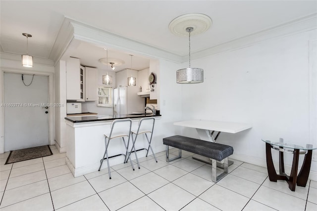 kitchen featuring pendant lighting, a breakfast bar area, white cabinets, kitchen peninsula, and crown molding