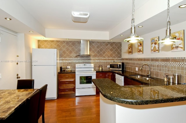 kitchen featuring sink, white appliances, decorative light fixtures, kitchen peninsula, and wall chimney exhaust hood